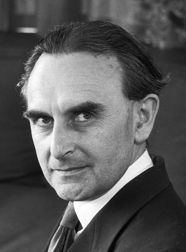 Richard Neutra seated in a cantilever chair holding a photograph of the Beard House