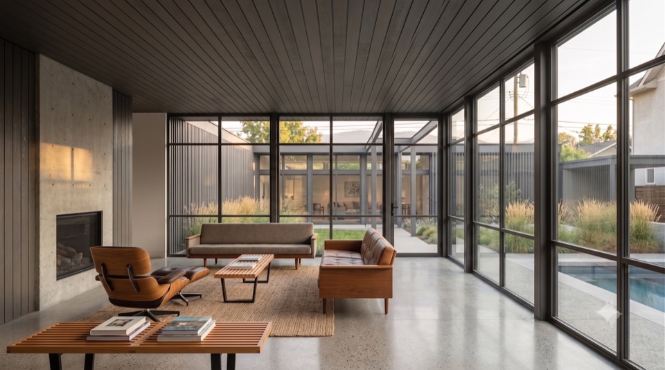Living room under light steel frame, a full wall of glass to the outside.