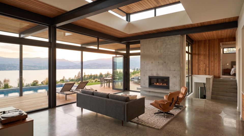 Living room under concrete terraces, a full wall of glass to the outside.